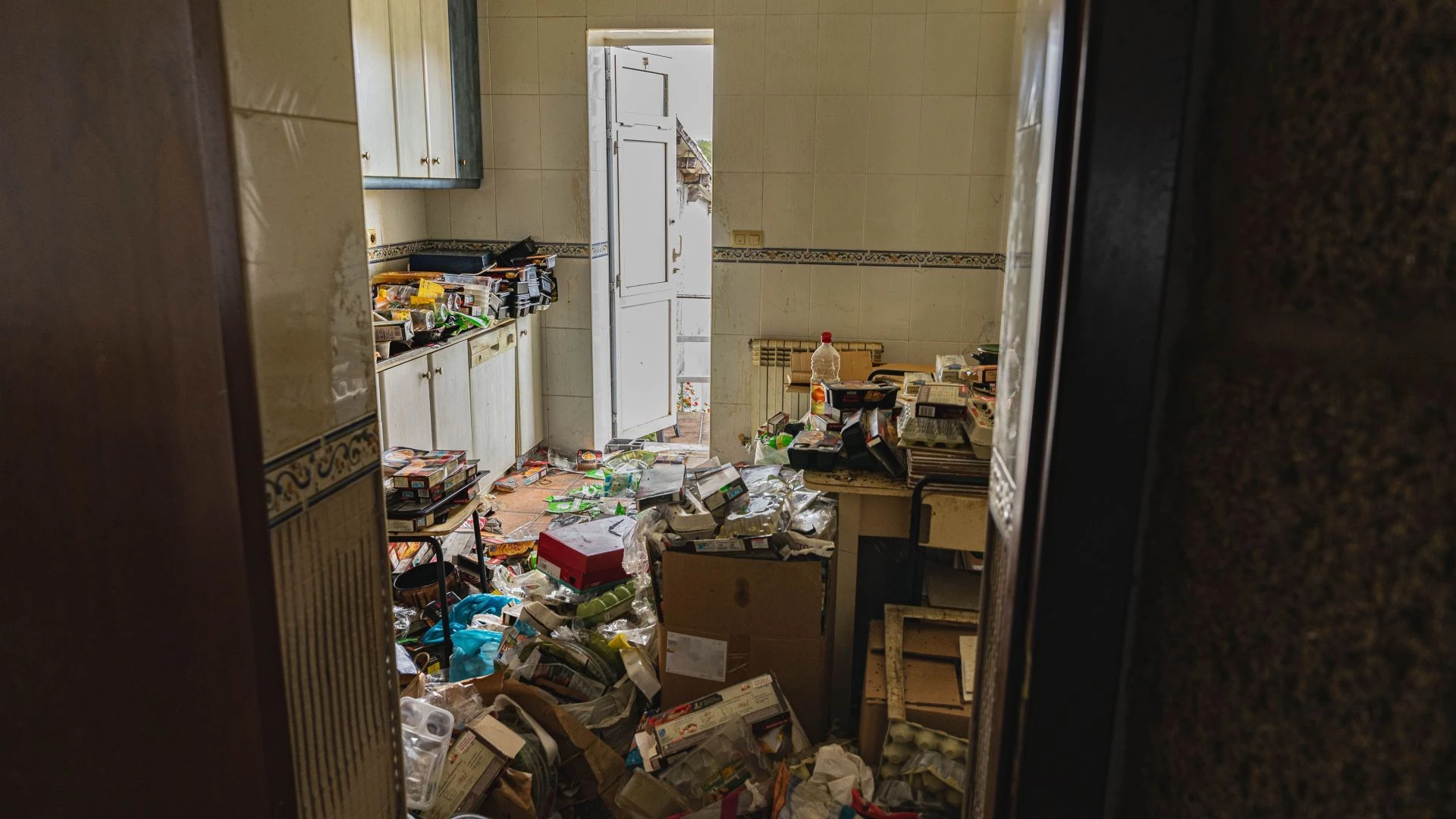 Cuisine d’un logement très encombré de déchets, cartons et emballages, illustrant une situation de syndrome de Diogène.