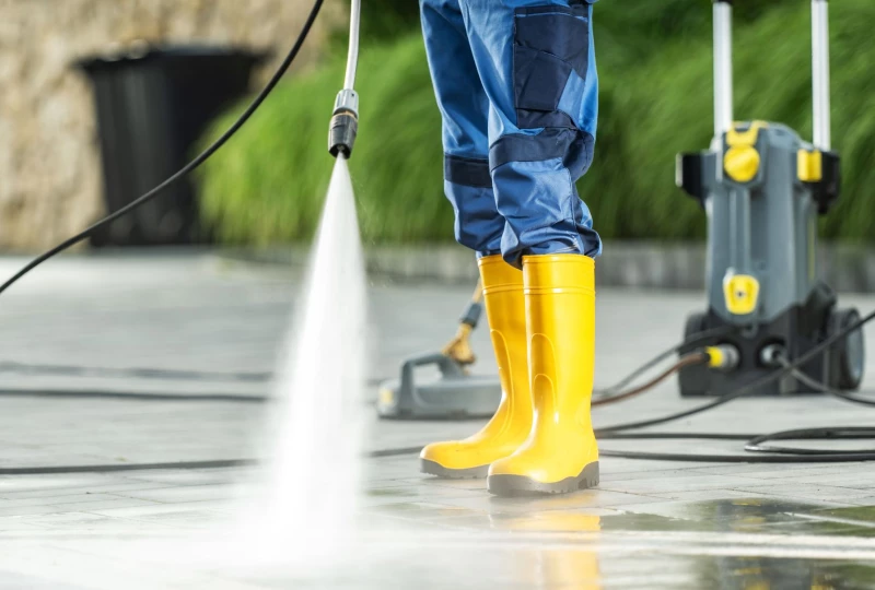 Personne effectuant un nettoyage à haute pression en extérieur avec des bottes jaunes