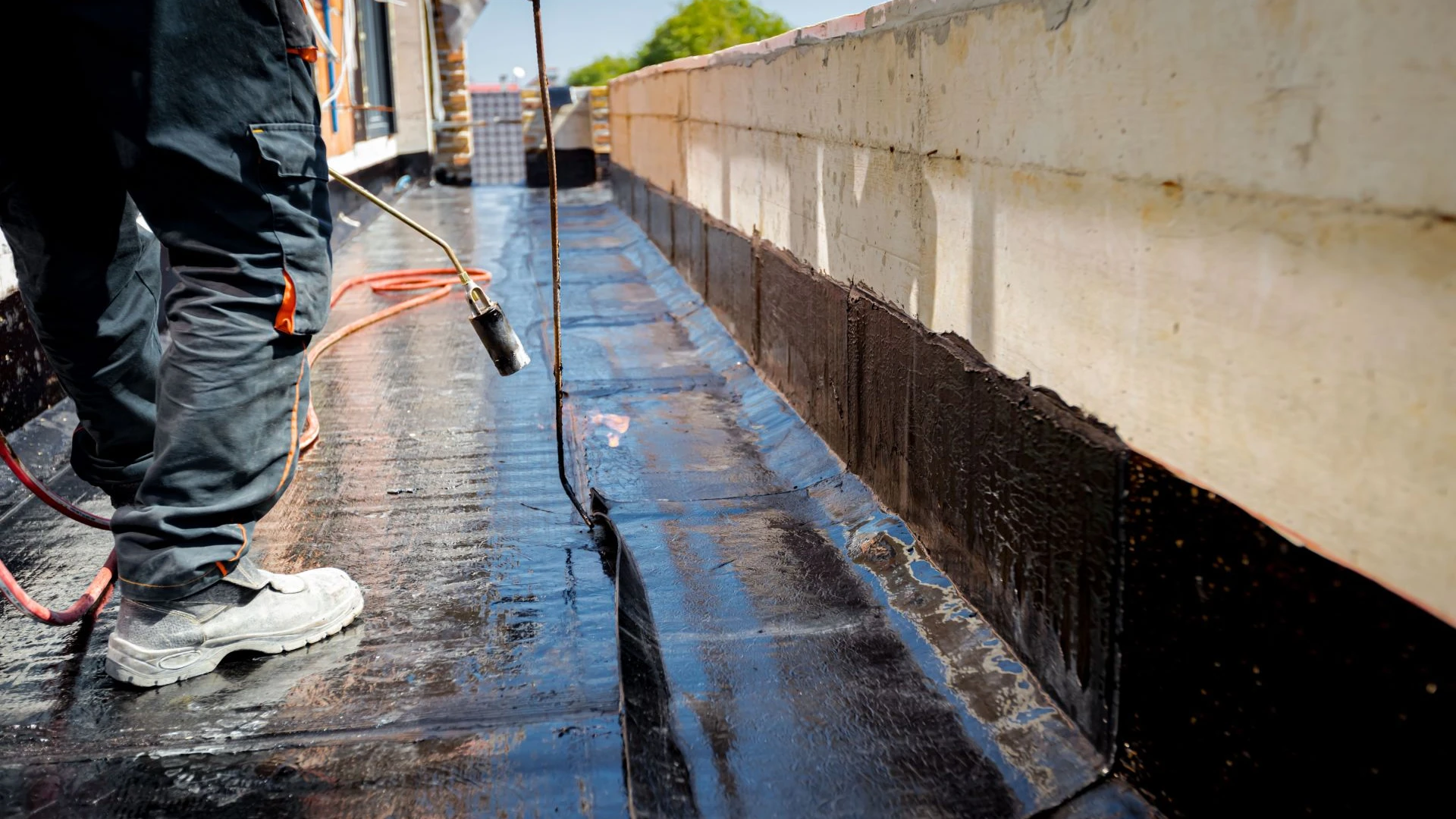 Technicien étancheur appliquant une résine d’étanchéité sur une toiture terrasse dans le Var